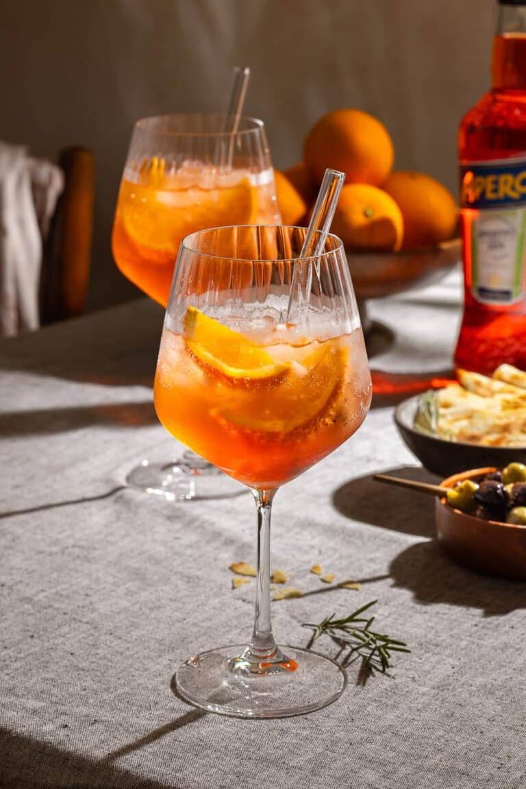 Aperol Spritz mit Orangenscheibe im Weinglas – hochwertige Cocktail-Fotografie mit Aperitif-Flasche und sommerlichem Bar-Ambiente