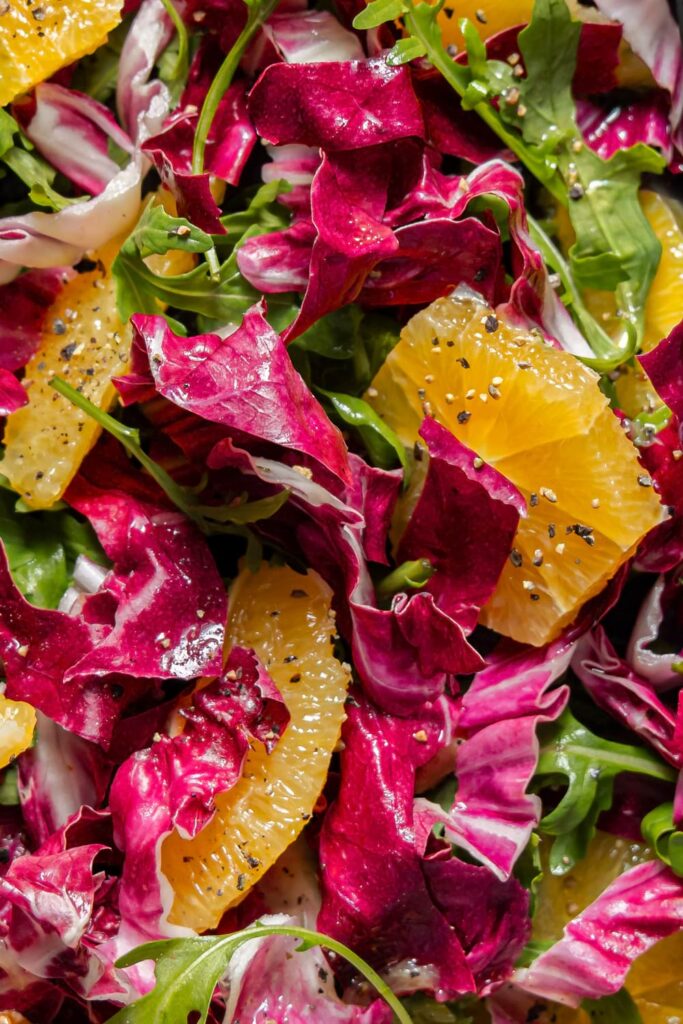 Bunter Orangen-Radicchio-Salat mit Rucola und schwarzem Pfeffer – Makro Food Fotografie im Close-up