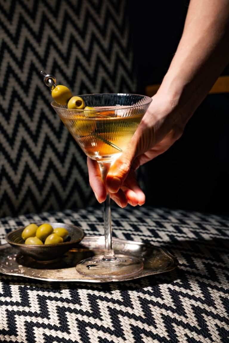 Klassischer Martini Cocktail mit grünen Oliven im Cocktailglas auf Silbertablett – professionelle Bar- und Getränkefotografie