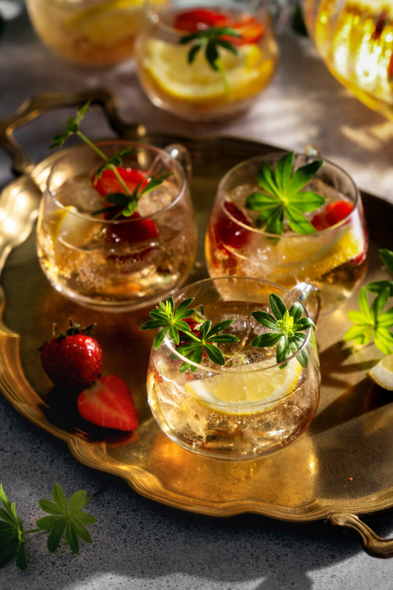Mai Bowle mit Waldmeister, frischen Erdbeeren und Zitronenscheiben, im warmen Licht der Abendsonne fotografiert – stimmungsvolle Food Fotografie für einen erfrischenden Sommerdrink